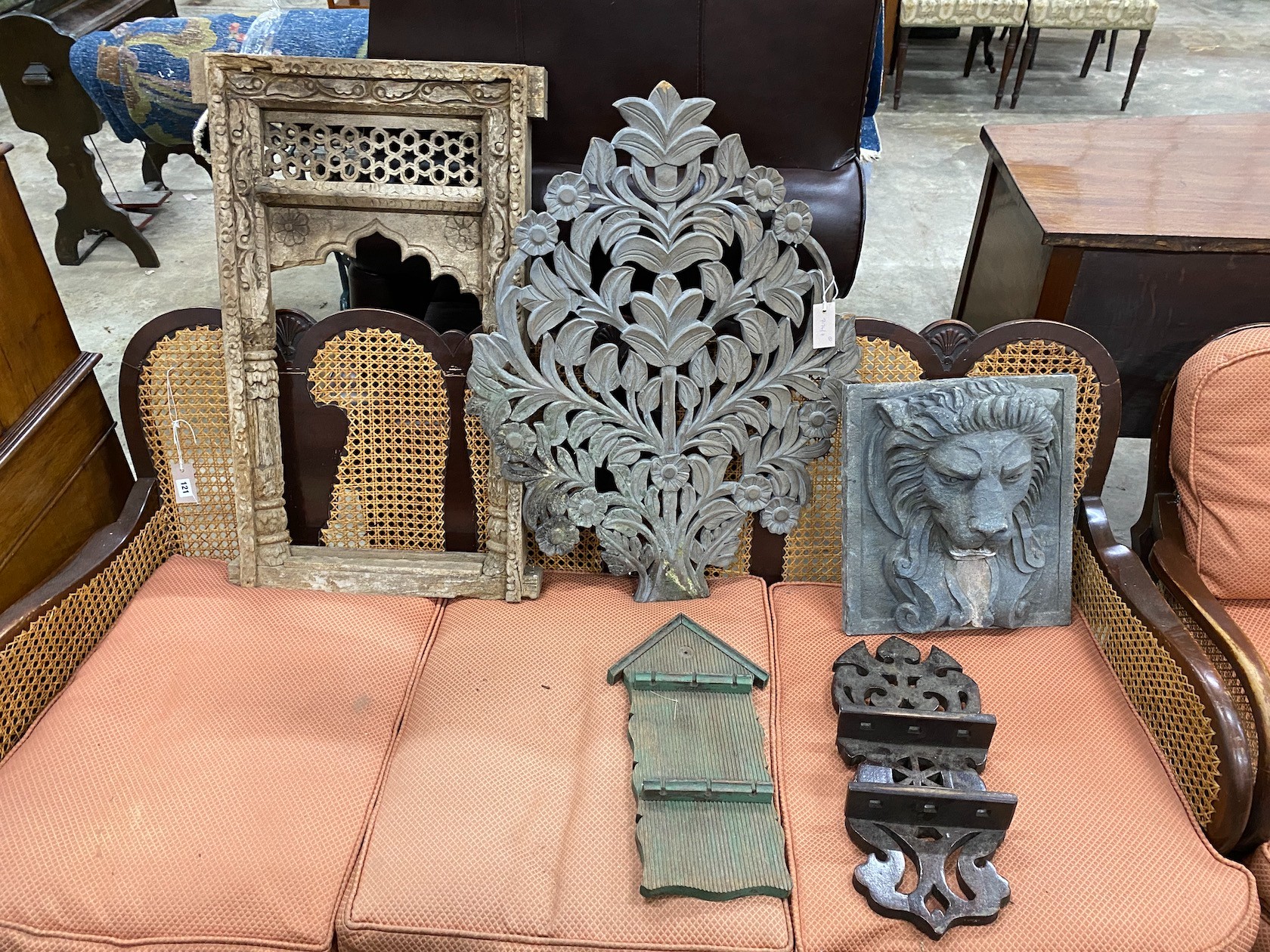 A carved Eastern hardwood window frame, height 82cm, a composition lion mask wall fountain two spoon racks and a composition wall hanging